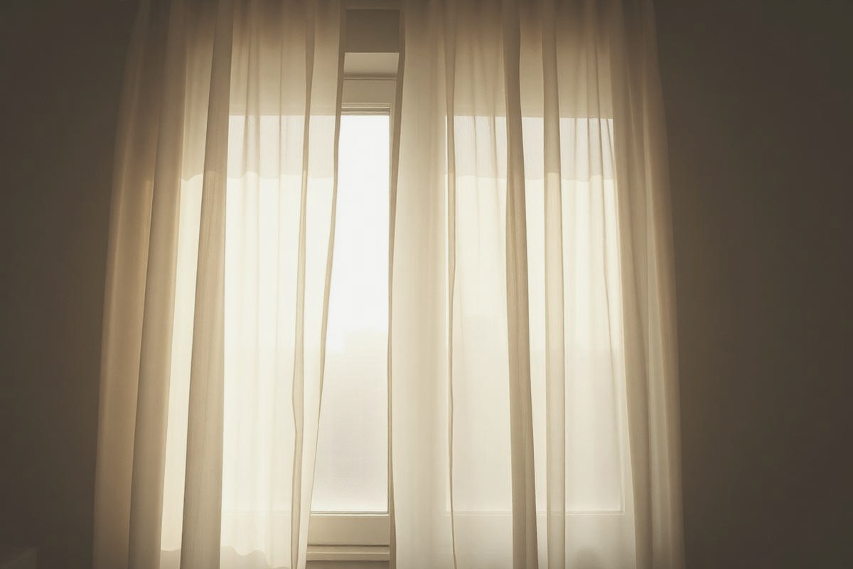 A sheer curtain breathing gently at an open window in soft morning light