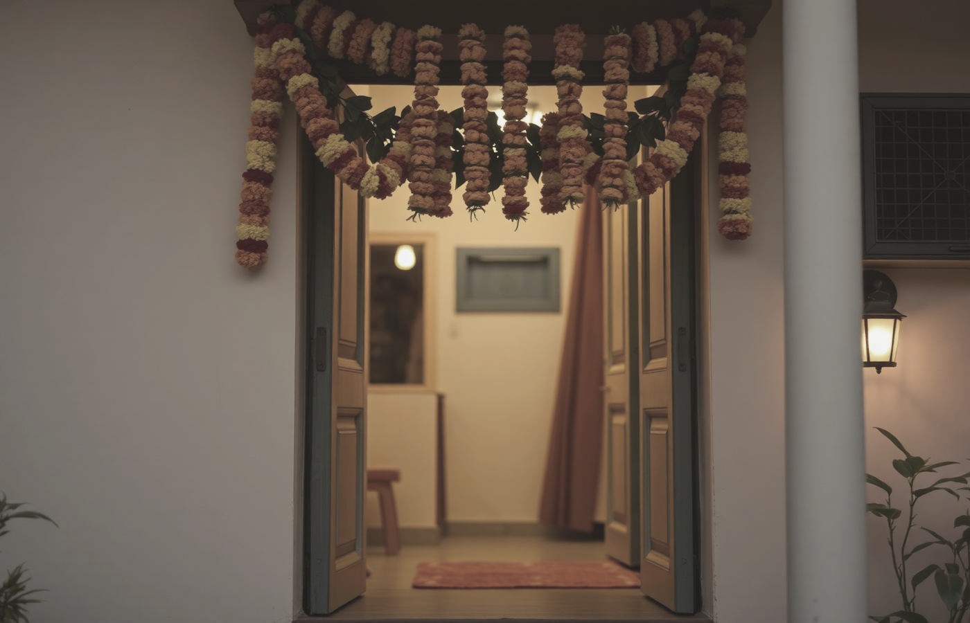 A warmly lit doorway hung with a marigold torana at dusk